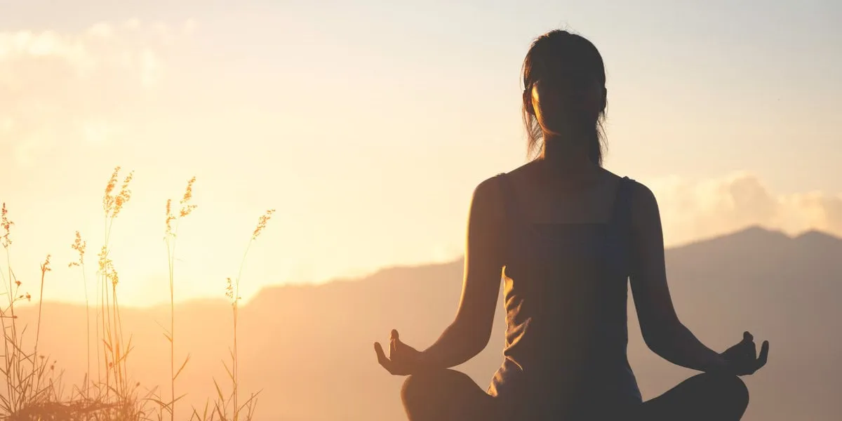silhouette fitness girl practicing yoga on mountain with sun light