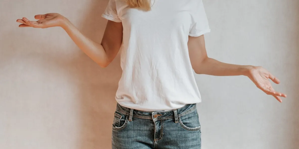 blond hair woman posing near a light wall beautiful young caucasian girl hand gestures emotion casual clothing studio model in work strong woman, future is female jeans and white blank t-shirt