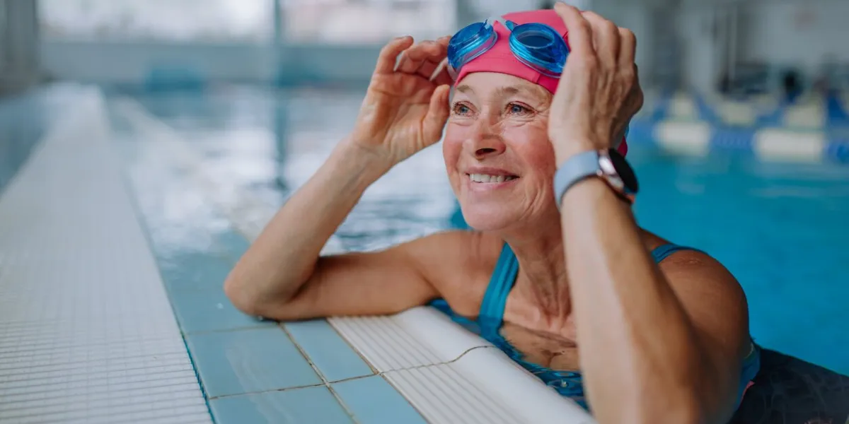 a happy senior woman in swimming pool, leaning on edge