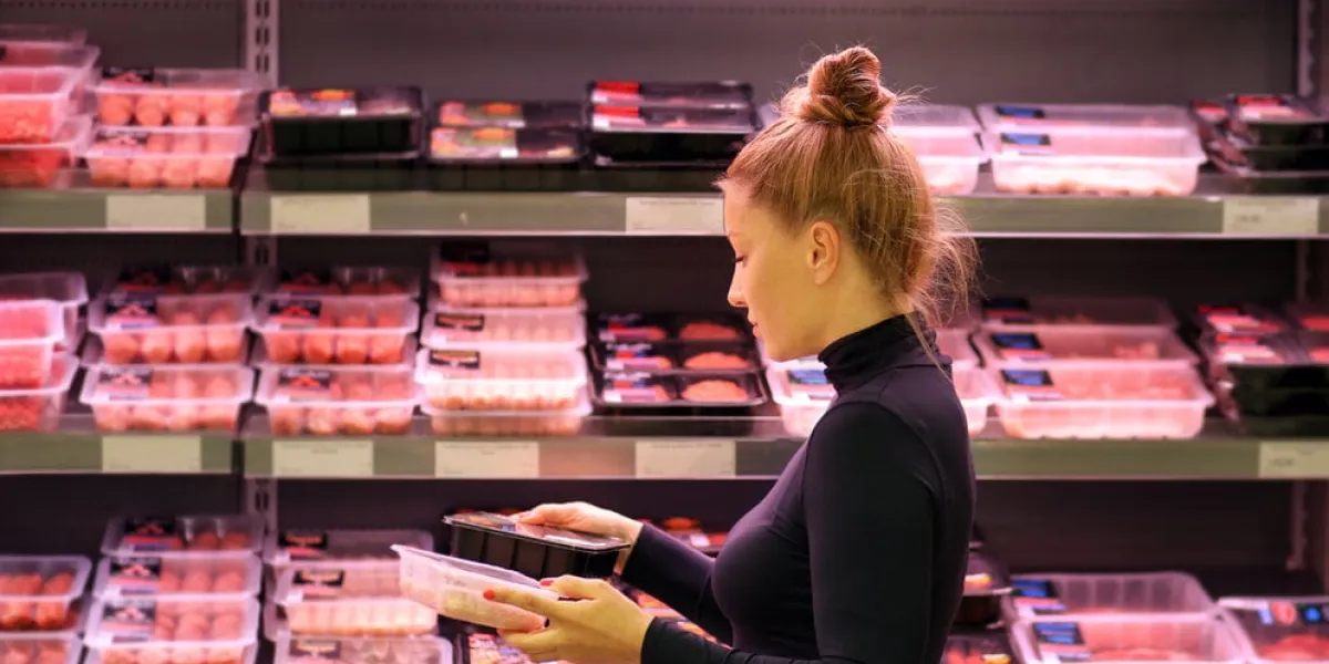 woman purchasing a packet of meat at the supermarket