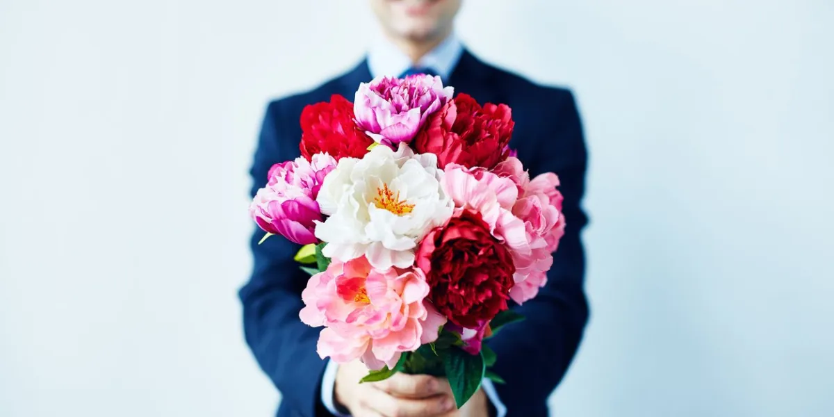 elegant man giving a beautiful bouquet of red and white flowers