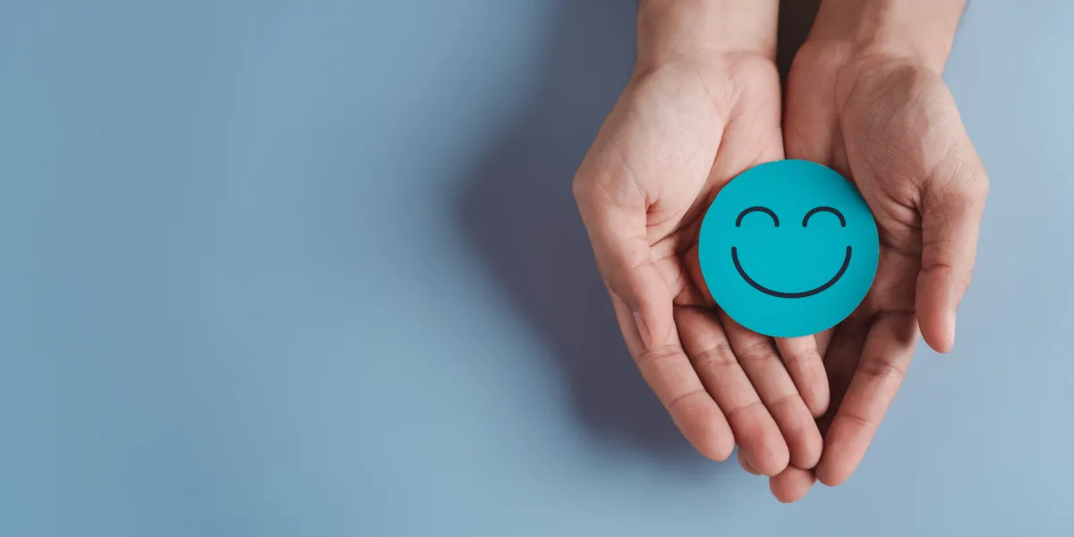 hands holding blue happy smile face, good feedback rating, positive customer review, experience, satisfaction survey, smiley mental health, child wellness, world mental health day on blue background