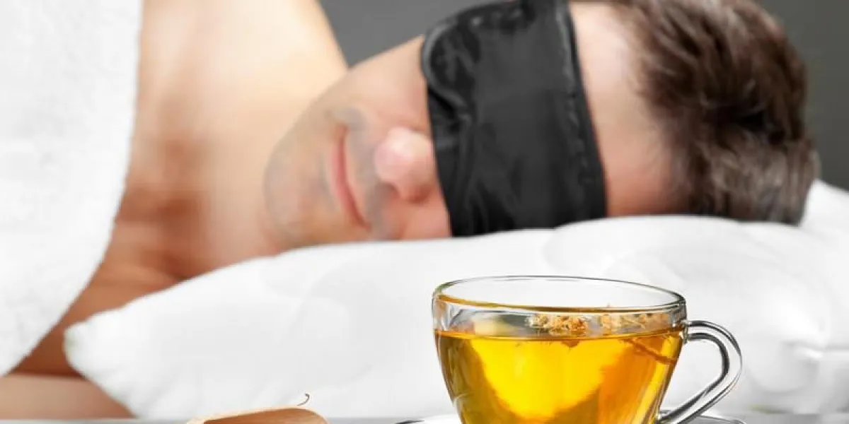 homme avec un masque de sommeil dormir sur un lit, une tasse de tisane au premier plan