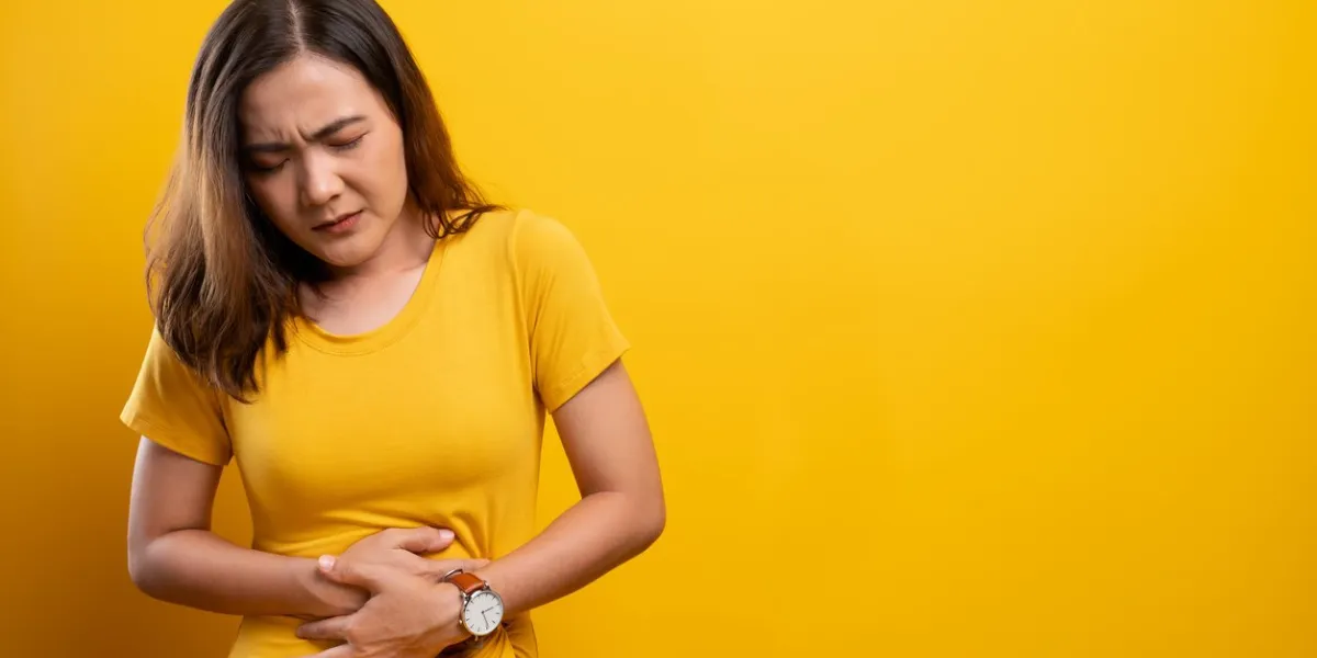 woman has stomachache isolated over yellow background