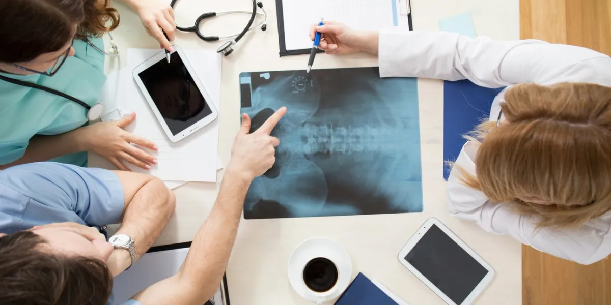 doctors sitting around the table and interpreting x-ray image