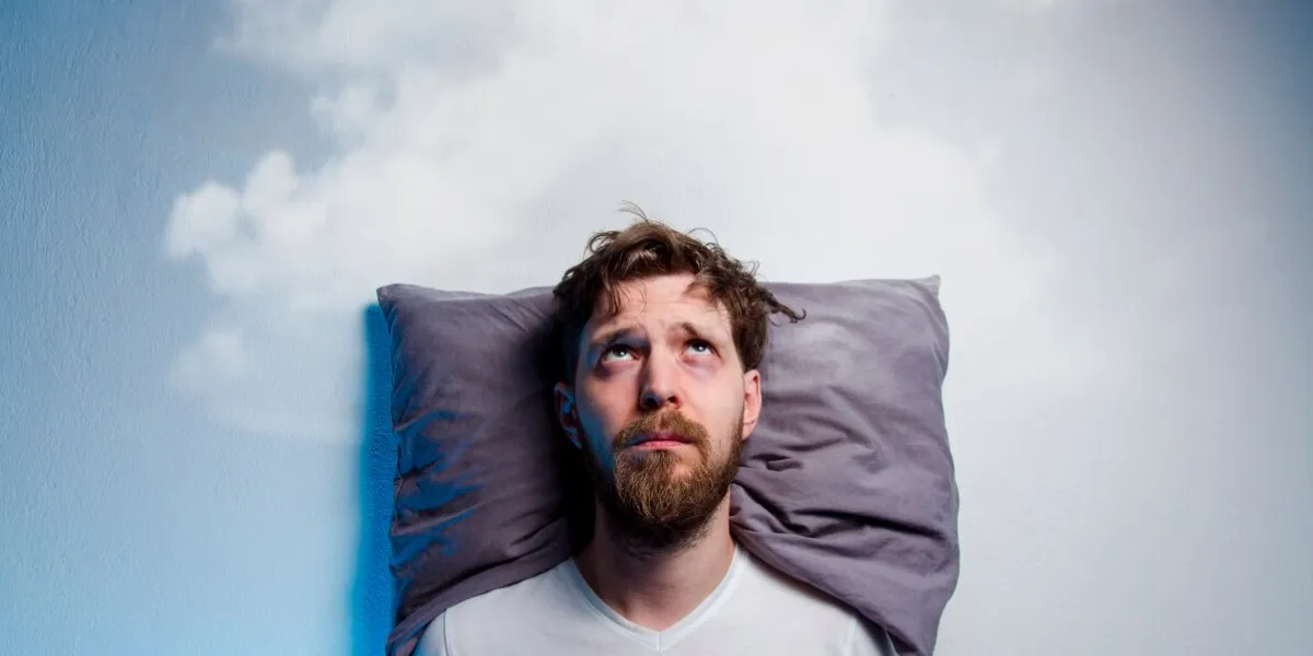 man having problems  insomnia, laying in bed on pillow, looking up to gray cloud over his head, copy space