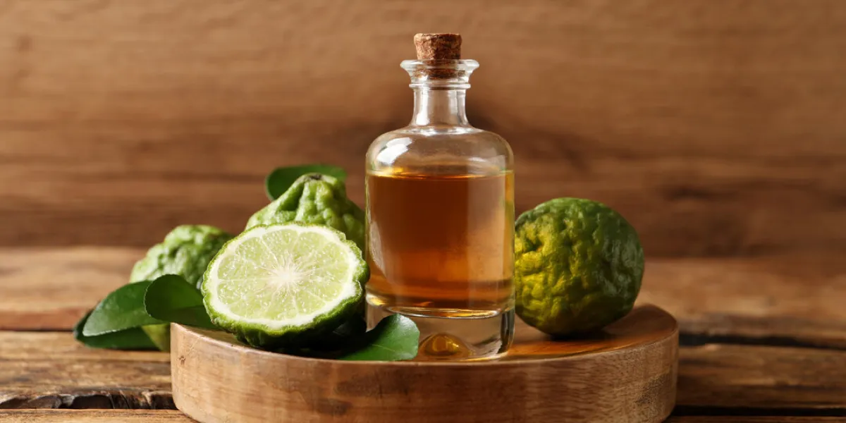 glass bottle of bergamot essential oil on wooden table