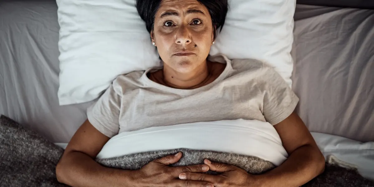 insomnia, portrait and senior woman in bed from above with menopause, anxiety or stress in her home top view, face and elderly female in a bedroom with depression, trauma or mental health crisis