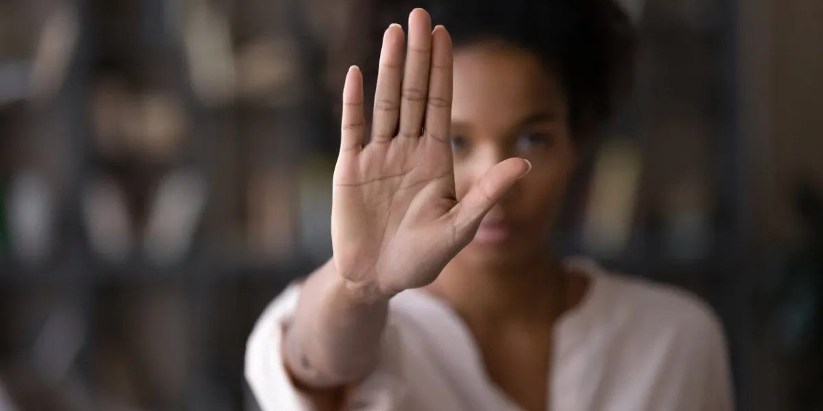 close up focus on female mixed race palm hand showing stop sign, serious african american woman protesting against bullying in society, sexual or racial discrimination, denying family abuse indoors