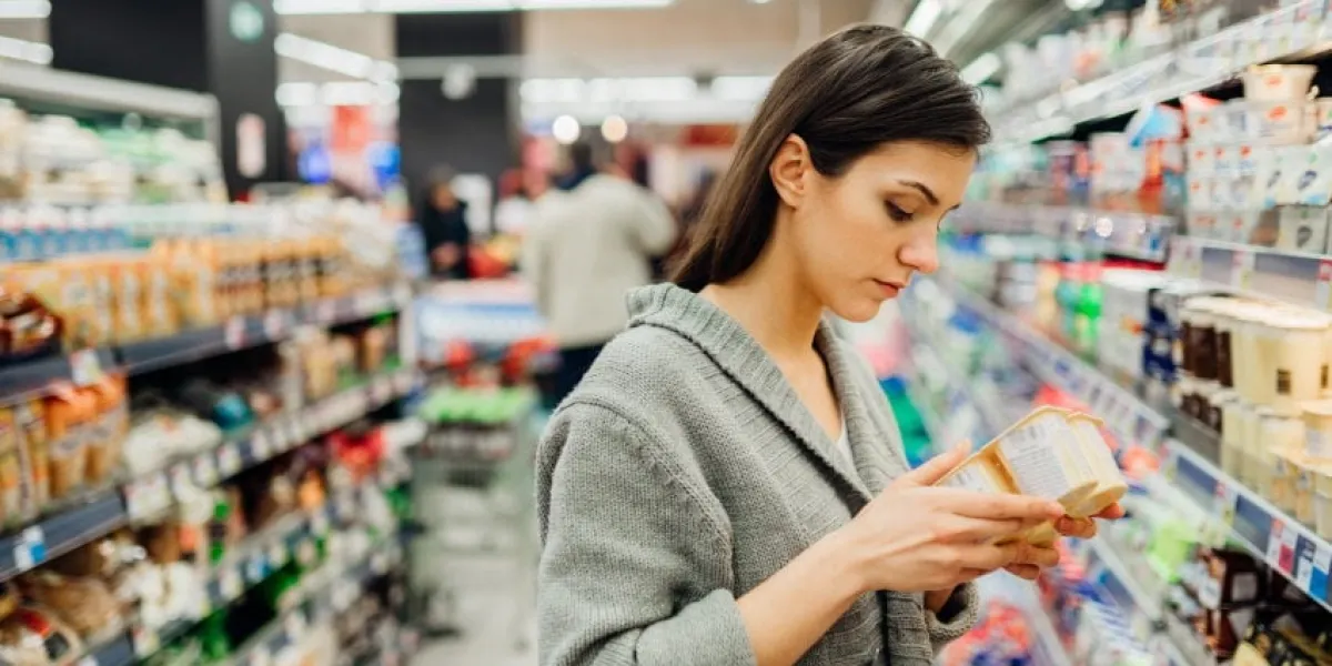 young woman shopping in the supermarket grocery storereading ingredients,declaration or expiration date on a dairy product before buying itnutritional values of the foodlactose intolerance