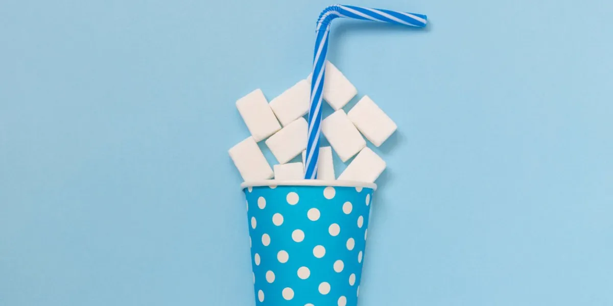 flat lay of paper cup polka design full of sugar cubes and drinking straw against pastel blue background minimal creative concept
