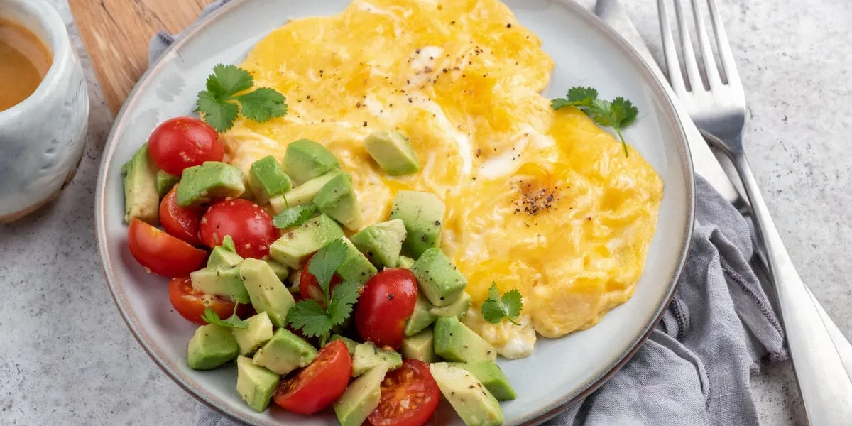 scrambled eggs omelet with cherry tomatoes and avocado