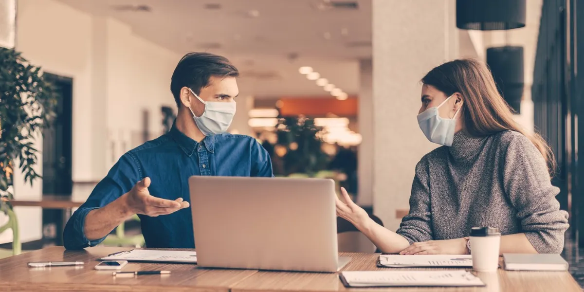 close up business colleagues in protective masks sitting at the office desk