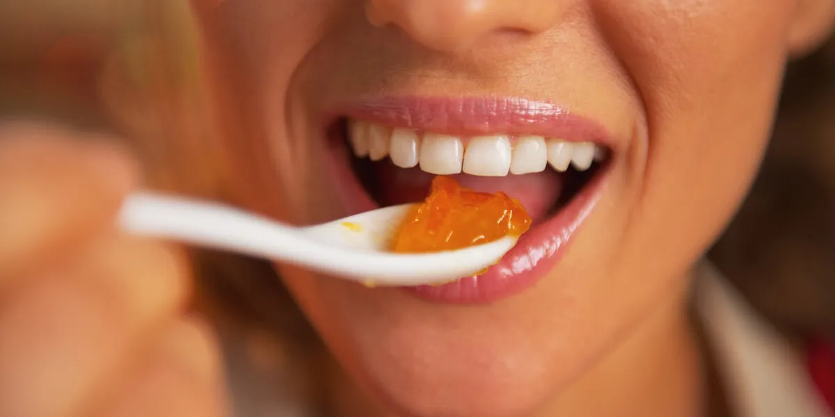 closeup on happy young woman eating orange jam