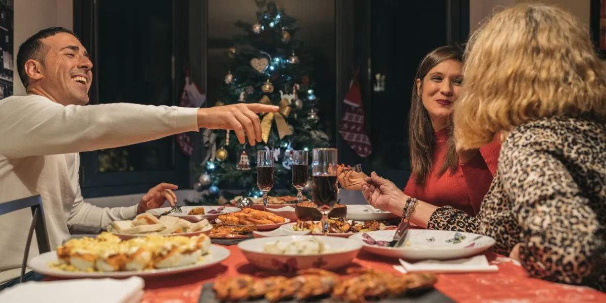 family having christmas dinner at home table full of food to celebrate christmas eve