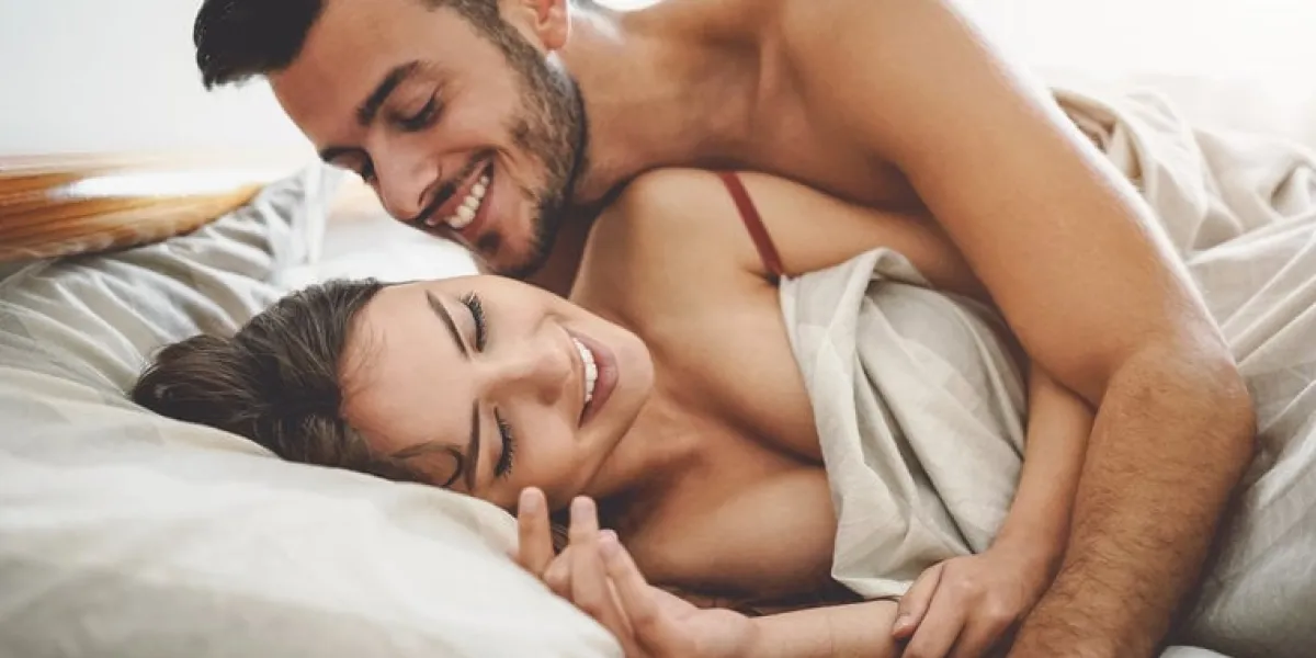 happy couple having fun on bed under blanket - young romantic lovers intimate moments - intimacy and love relationship concept
