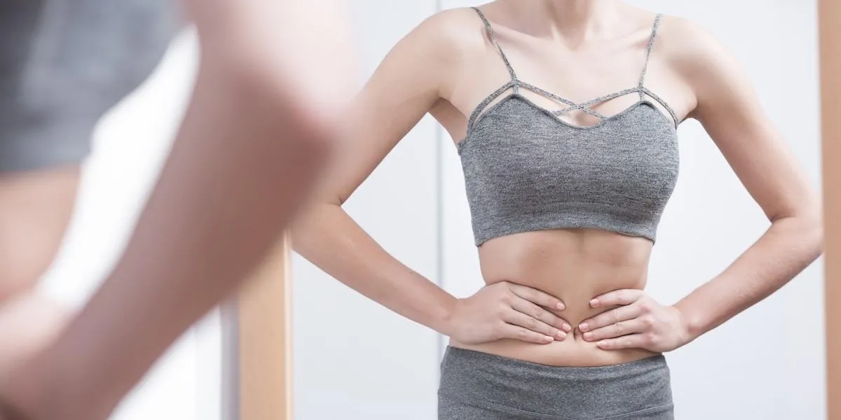 skinny girl holding her waist looking in mirror