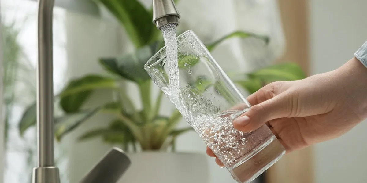 woman filling glass with water from tap at home, closeup
