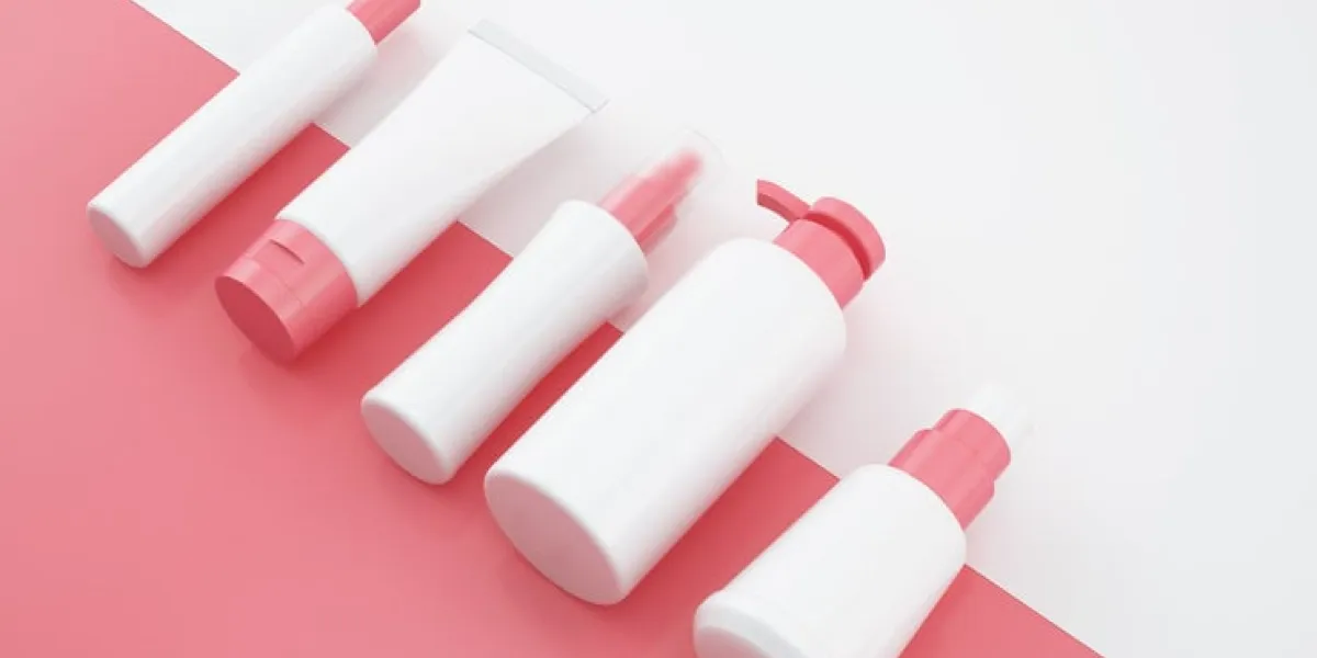 group of cosmetic products in pink color on white background