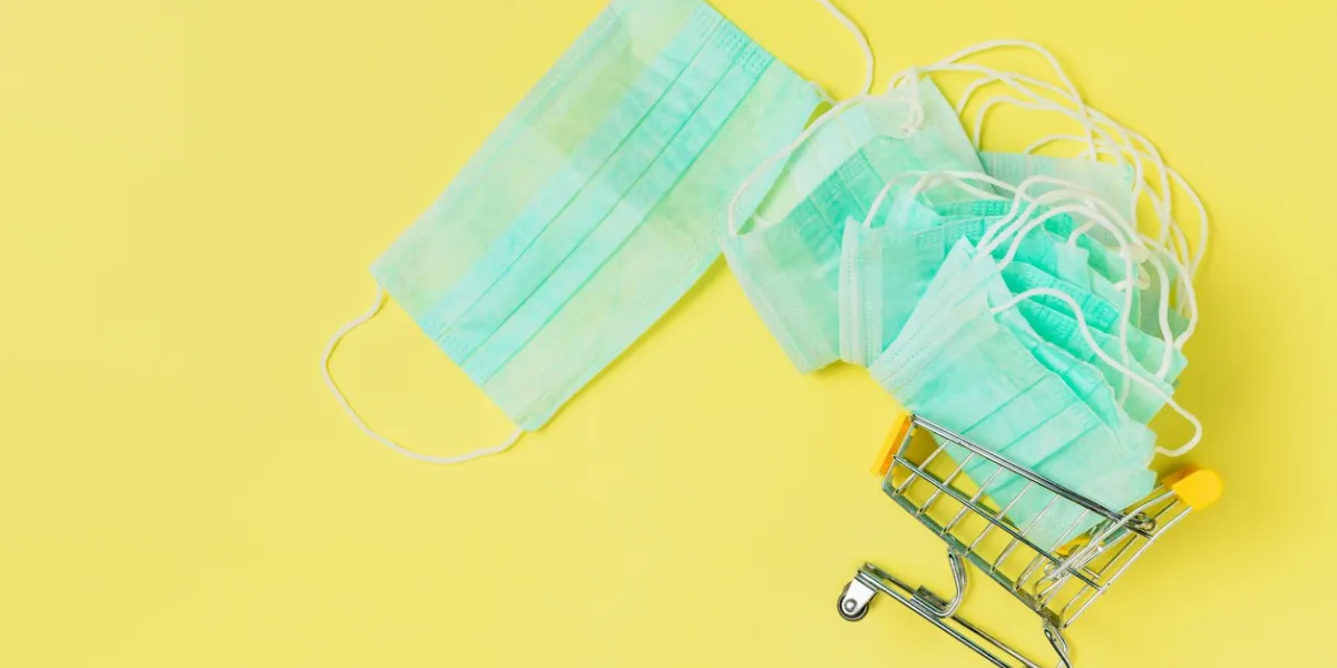 medical mask in a shopping cart, trolley on yellow background, personal protective and shopping concept