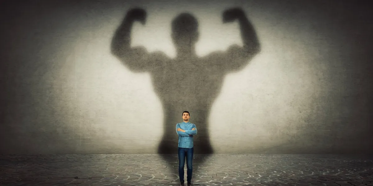 confident businessman imagine himself a powerful hero, casting shadow of big strong muscular bodybuilder showing his biceps inner strength, leadership qualities business development
