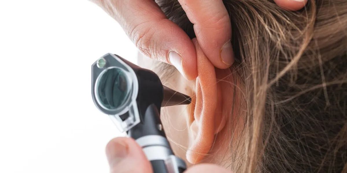 closeup of examining ear with an otoscope