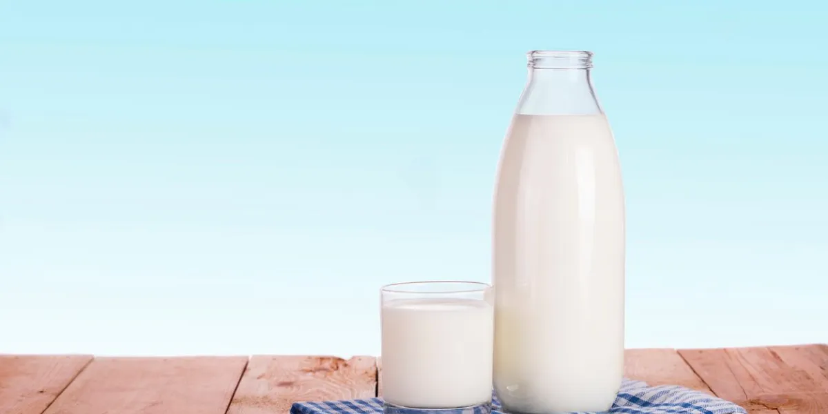 bottle of fresh milk and glass is wooden table