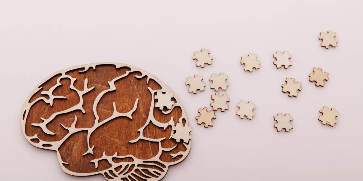 alzheimer's disease and mental health concept brain and wooden puzzle on a pink background