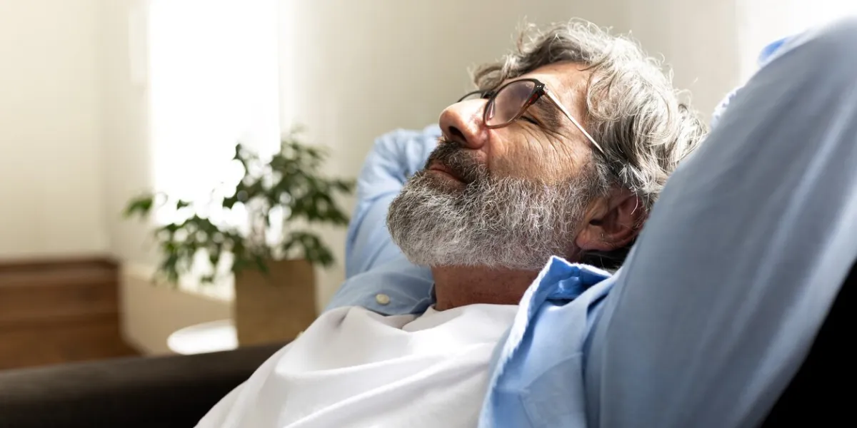 mature man relaxing at home sitting on the sofa with hands behind the head feeling satisfaction copy space lifestyle concept
