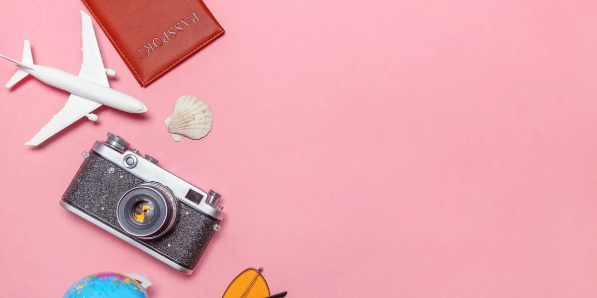 vacation travel summer weekend sea adventure trip concept minimal simple flat lay with plane vintage camera passport sunglasses globe piggy bank and shell on pink pastel trendy modern background
