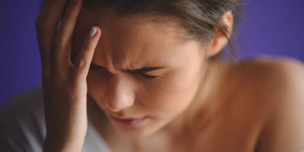 teen woman with headache holding her hand to the head