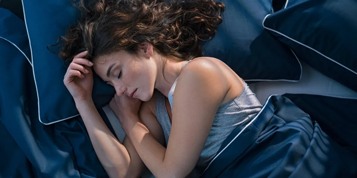 top view of young woman sleeping on side in her bed at night beautiful girl sleeping profoundly and dreaming at home with blue blanket high angle view of woman asleep with closed eyes