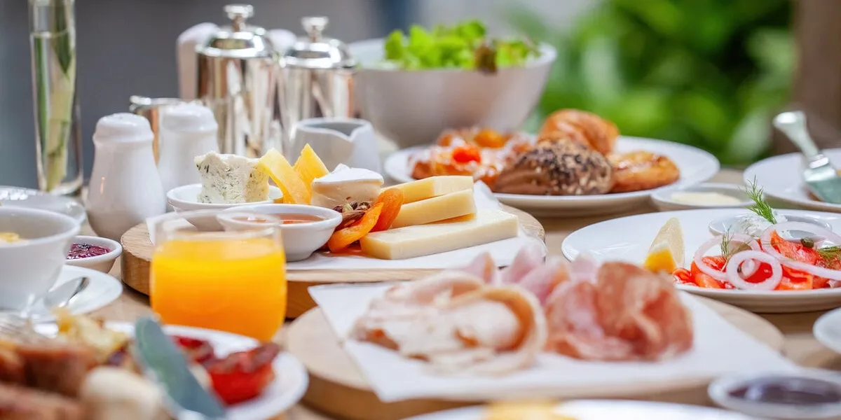 table full of various fresh food in luxury modern restaurant delicious dishes, cold cuts, salmon, omelette, pastries, juices, cheese delicious and lavish breakfast or morning meal in high-end hotel