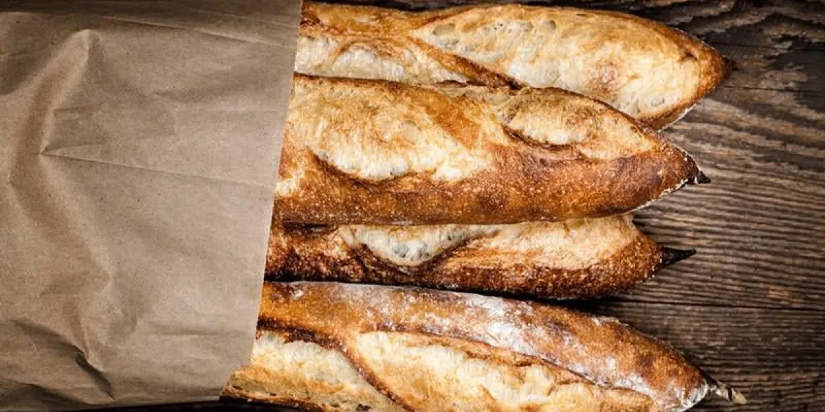 quatre pains baguette baguette dans un sac en papier sur fond en bois