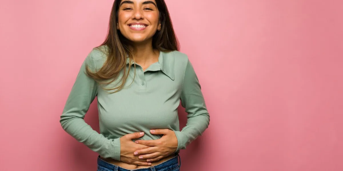 the food was delicious satisfied young woman smiling and rubbing her full stomach after eating lunch