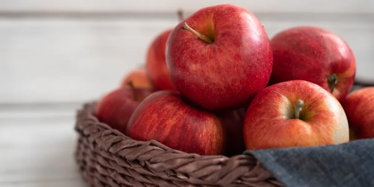 fresh red apples in a wicker basket ripe fruits as a concept of a plentiful harvest white background wooden table