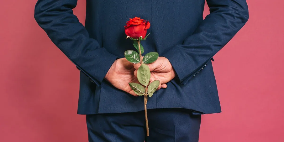 unrecognizable charming well dressed man holding a red rose