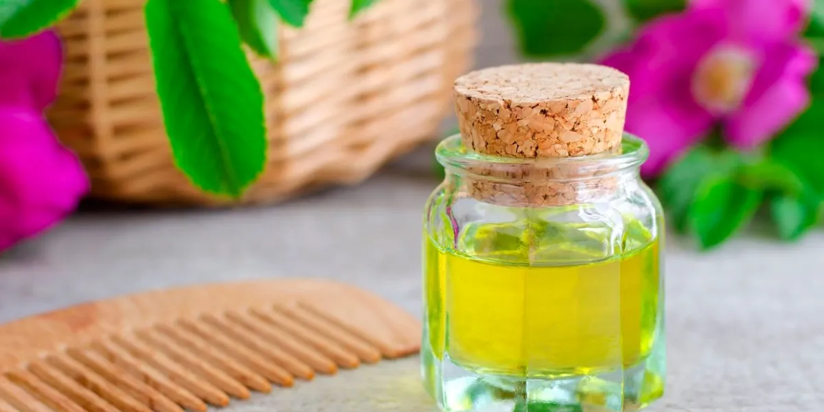 small bottle of natural cosmetic (massage) oil and wooden hair comb