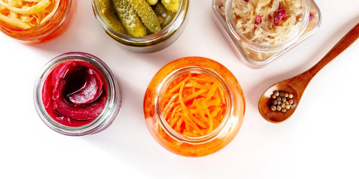 fermented food on a white background with a place for text canned sauerkraut, carrot, pickles and other preserves in glass jars homemade vegan cooking probiotic foods