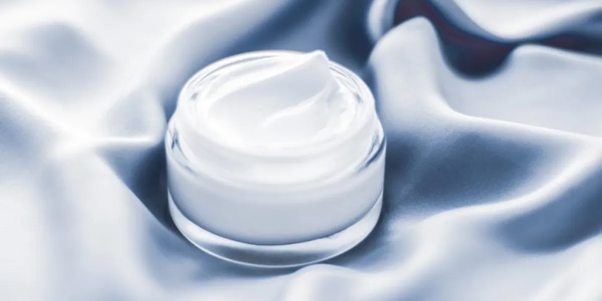 spa, anti-age cosmetics and skincare concept - beauty face cream jar on a soft blue silk