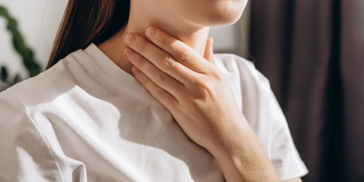 cropped shot of female suffering from pain sitting on sofa at home healthcare and medical concept unhealthy sad young caucasian woman with sore throat inflamed tonsils from influenza symptoms