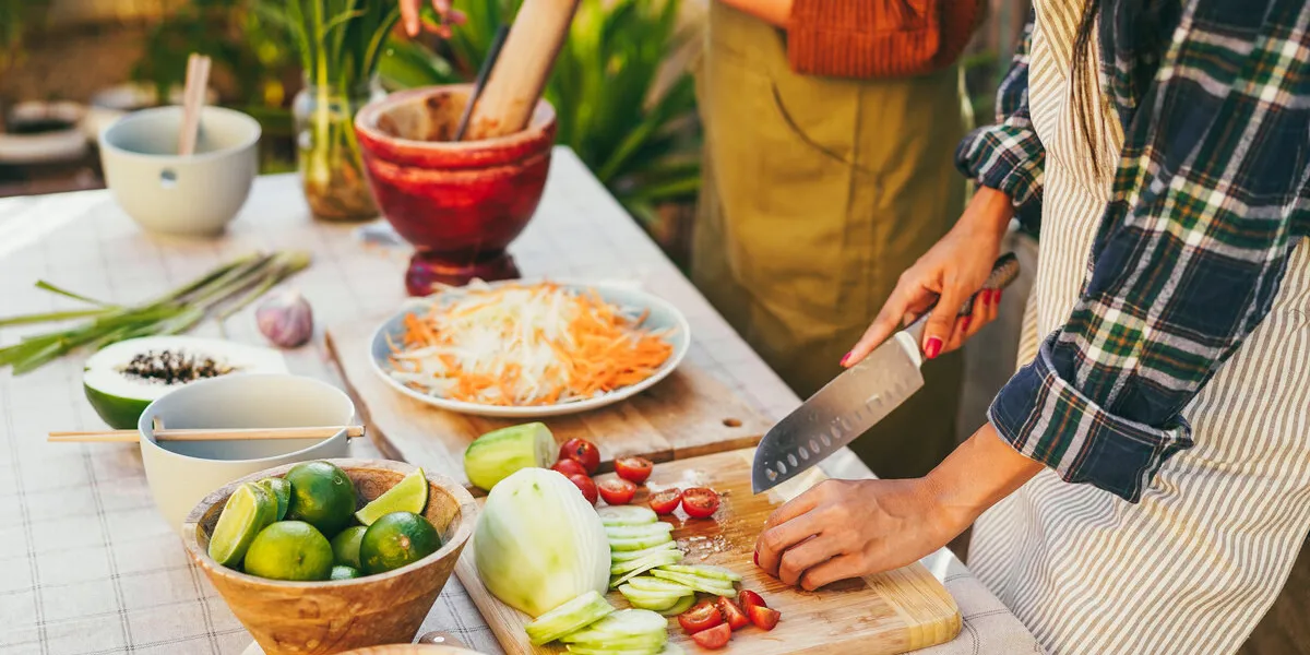asian family cooking thai dinner together while preparing papaya salas at home patio outdoor - main focus on on right hand