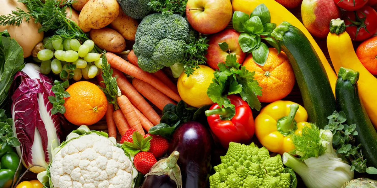 different colorful fruits and vegetables all over the table in full frame studio shot