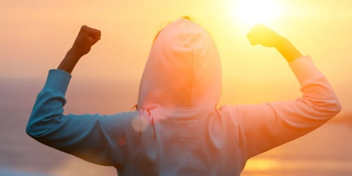 back view of strong motivated woman celebrating workout goals towards the sun morning healthy training success