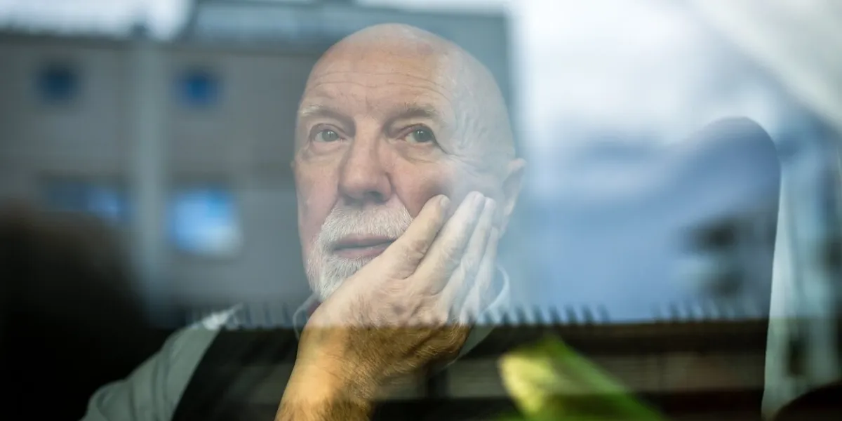 portrait of thoughtful senior man looking through window