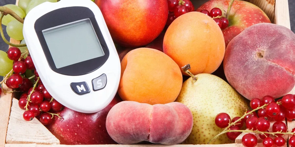 glucometer foe measuring sugar level and fresh fruits in wooden box as healthy snack or dessert containing natural vitamins and minerals