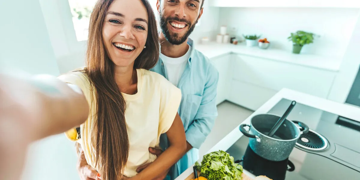 young happy couple preparing healthy meal in kitchen at home - husband and wife cooking salad - food and healthy lifestyle concept