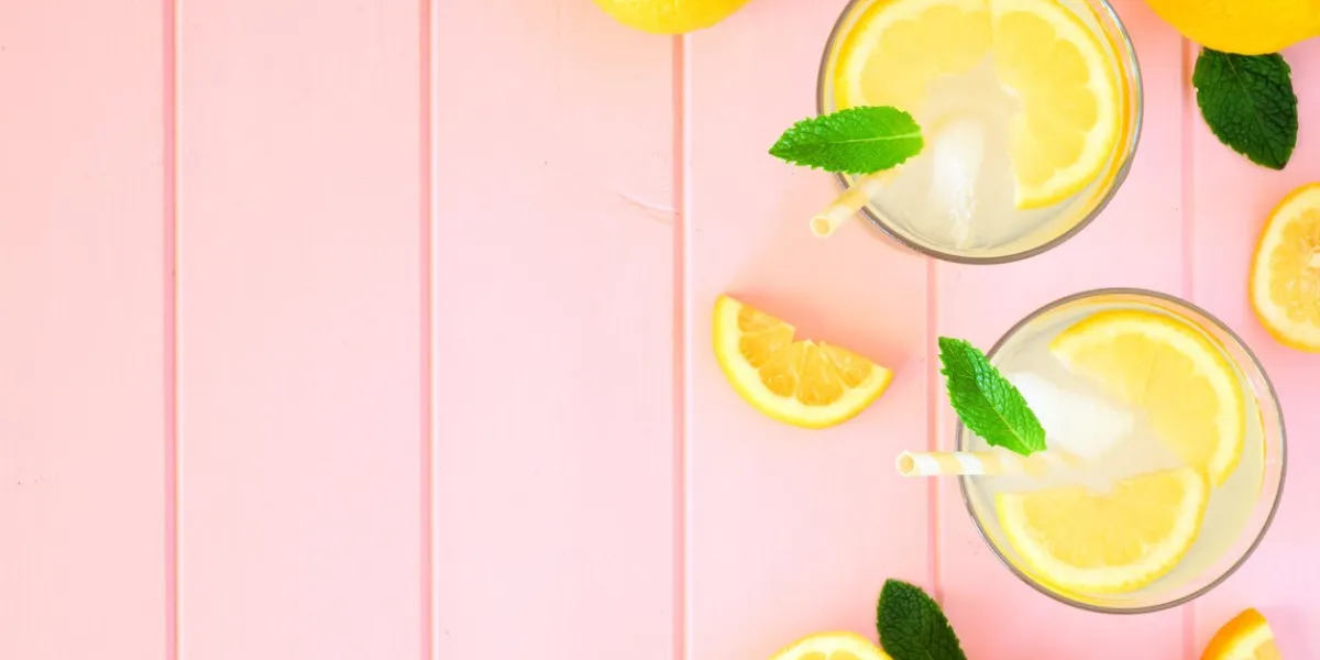 sweet summer lemonade top view side border with copy space on a pastel pink wood background