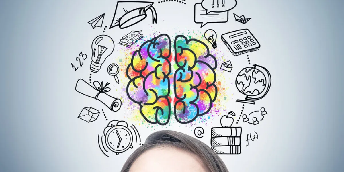 close up of a blonde woman s head she is standing near a gray wall and looking upwards an education drawing and a brain sketch on the wall