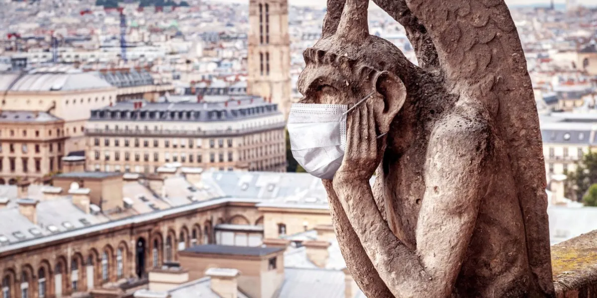 covid-19 coronavirus in france, medical mask on gargoyle of notre dame in paris tourist landmarks closed due to corona virus outbreak concept of travel, quarantine and covid coronavirus pandemic